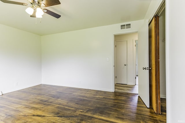 unfurnished room with visible vents, a ceiling fan, dark wood finished floors, and baseboards