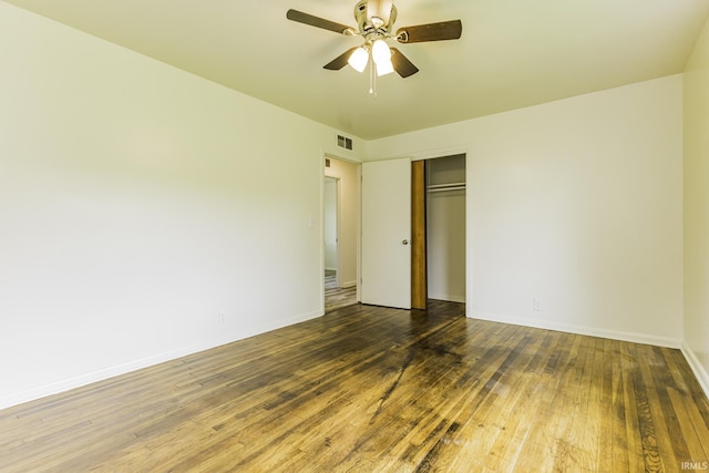 unfurnished bedroom with a ceiling fan, visible vents, wood finished floors, baseboards, and a closet