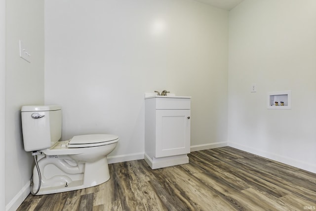half bath featuring toilet, baseboards, and wood finished floors
