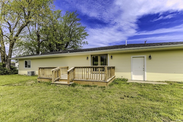 rear view of house with a yard, a wooden deck, and central AC unit
