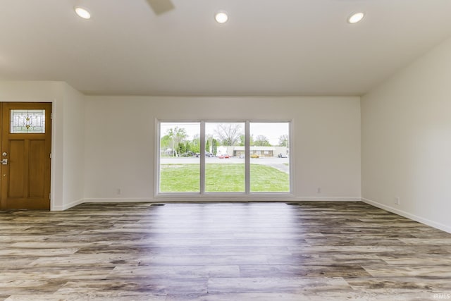 unfurnished living room featuring baseboards, recessed lighting, and wood finished floors
