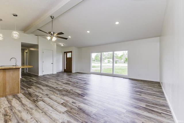unfurnished living room with baseboards, ceiling fan, lofted ceiling with beams, and wood finished floors