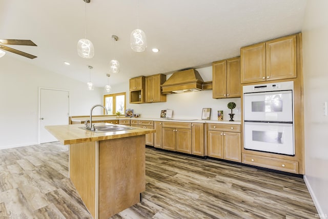 kitchen featuring white double oven, a sink, premium range hood, and wood finished floors