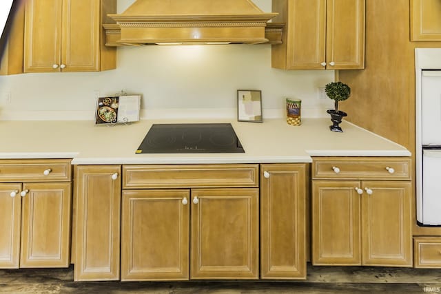 kitchen with light countertops, black electric stovetop, and premium range hood