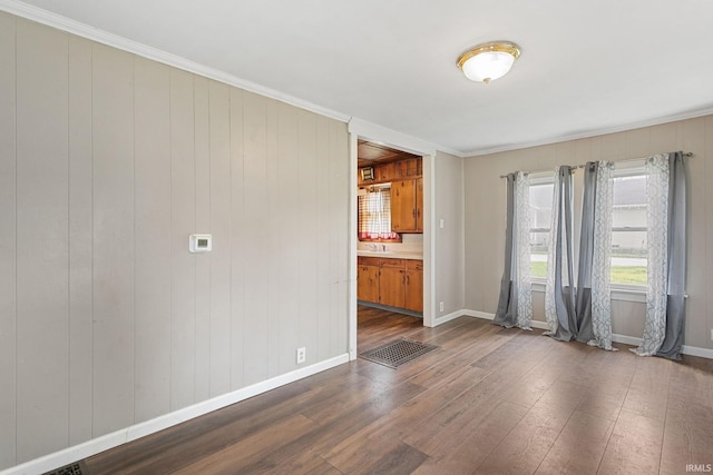 unfurnished room featuring baseboards, dark wood finished floors, and ornamental molding