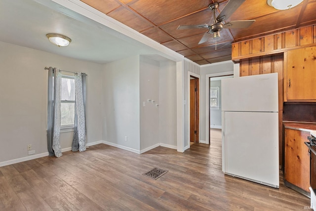 kitchen with visible vents, freestanding refrigerator, wood finished floors, baseboards, and ceiling fan