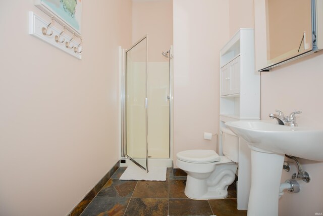 full bath featuring baseboards, a stall shower, stone finish floor, and toilet