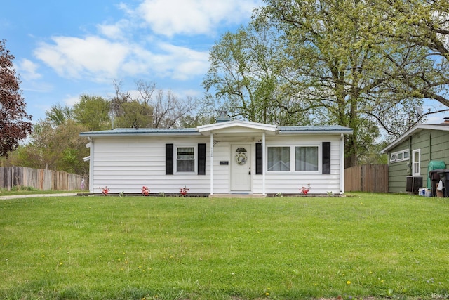 ranch-style house with fence, metal roof, and a front lawn