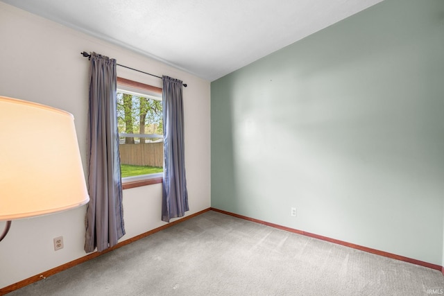 carpeted empty room featuring baseboards
