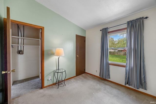 unfurnished bedroom with carpet flooring, baseboards, and vaulted ceiling
