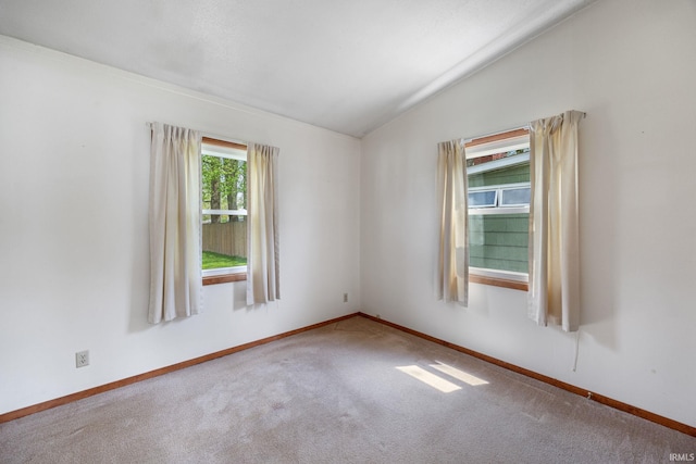 carpeted empty room featuring baseboards and lofted ceiling