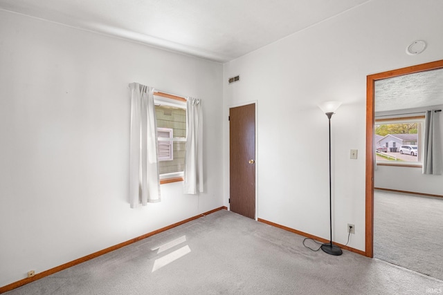 carpeted spare room featuring baseboards and visible vents