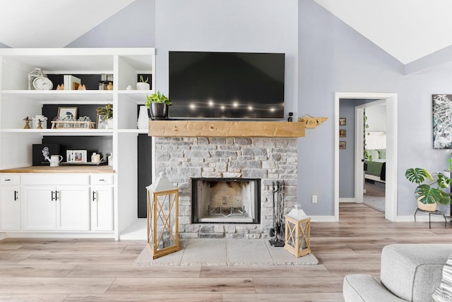 living area featuring a fireplace, high vaulted ceiling, built in shelves, baseboards, and light wood-type flooring