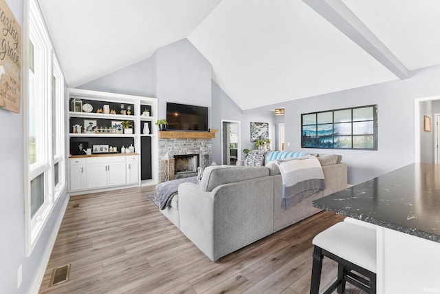 living room featuring visible vents, light wood-style floors, high vaulted ceiling, and a fireplace