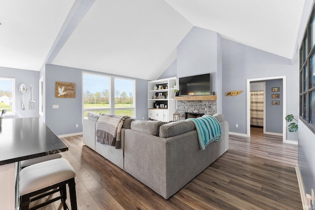 living area featuring high vaulted ceiling, dark wood-style floors, a healthy amount of sunlight, and a fireplace