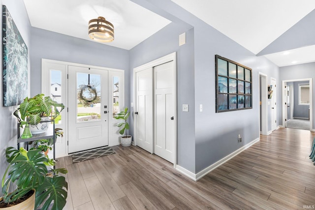 entryway featuring baseboards, wood finished floors, and lofted ceiling