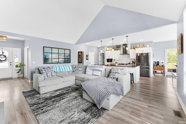 living room featuring visible vents, recessed lighting, light wood-style flooring, and high vaulted ceiling