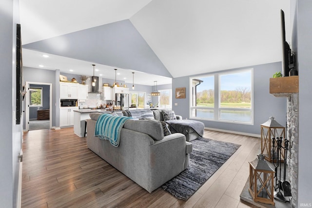living room with recessed lighting, high vaulted ceiling, and wood finished floors