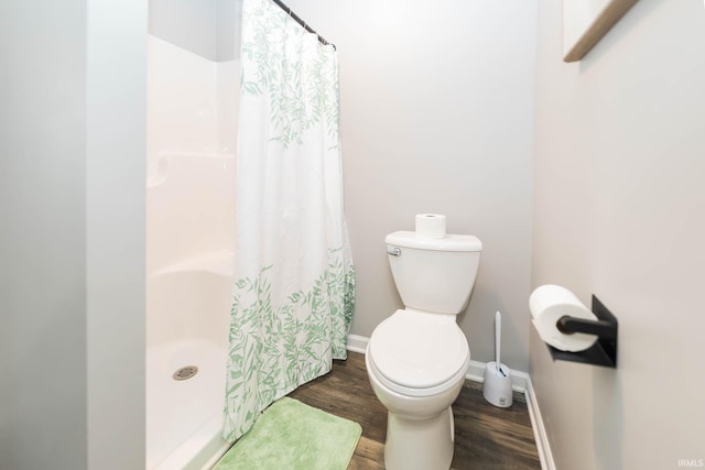 bathroom featuring baseboards, toilet, wood finished floors, and a shower with shower curtain