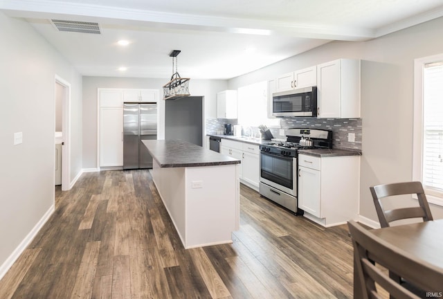 kitchen featuring dark countertops, tasteful backsplash, stainless steel appliances, and visible vents
