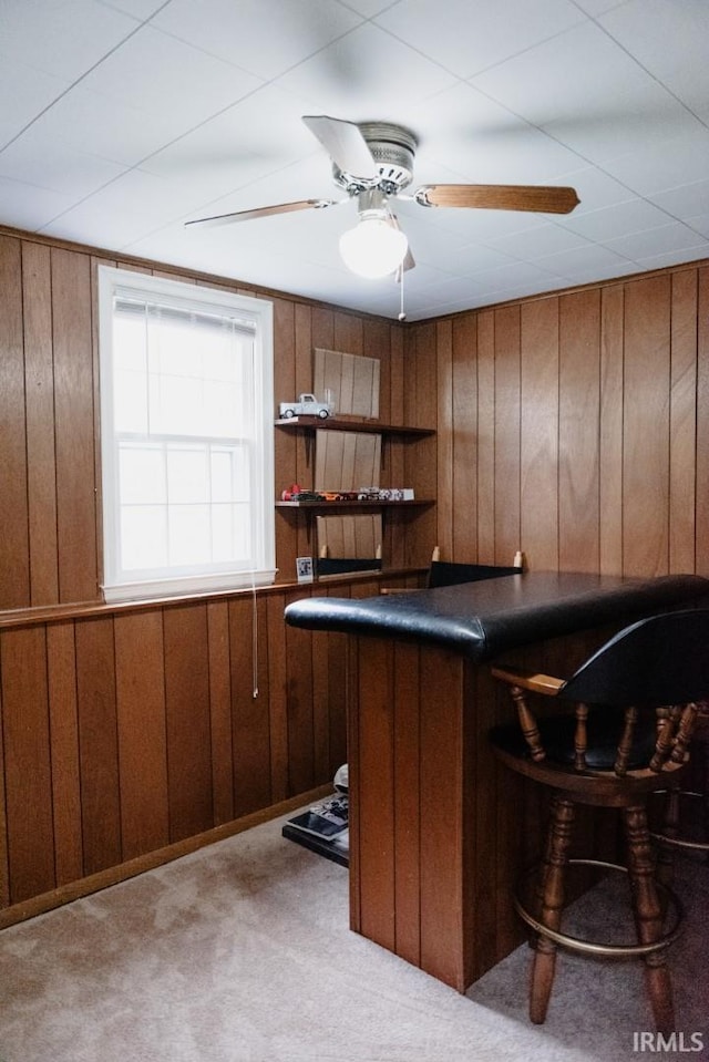 bar with a dry bar, ceiling fan, wooden walls, and carpet flooring