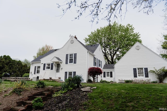 back of property featuring a lawn, a shingled roof, entry steps, and a chimney