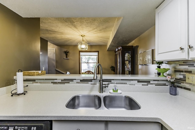 kitchen with a sink, white cabinetry, backsplash, and light countertops