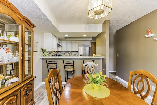 dining space featuring a textured ceiling, visible vents, wood finished floors, baseboards, and recessed lighting