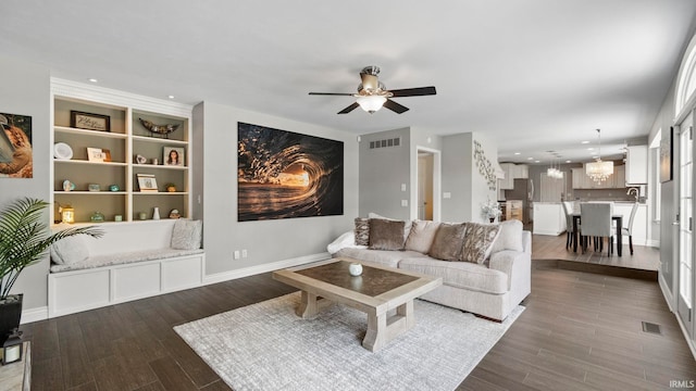 living area featuring visible vents, baseboards, ceiling fan with notable chandelier, and dark wood-style floors