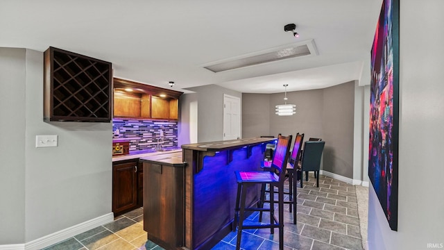 bar with backsplash, wet bar, pendant lighting, and baseboards