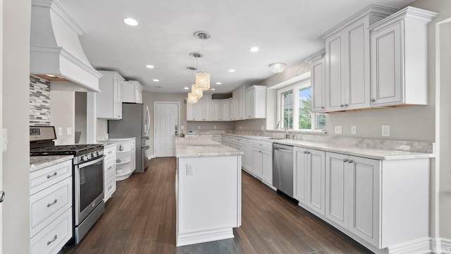 kitchen with a kitchen island, appliances with stainless steel finishes, a sink, a notable chandelier, and custom range hood