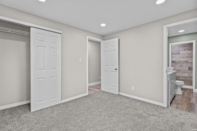 unfurnished bedroom with recessed lighting, ensuite bath, carpet, and a closet