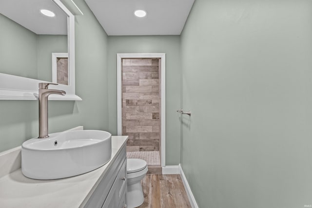 full bath with vanity, wood finished floors, toilet, baseboards, and a shower stall