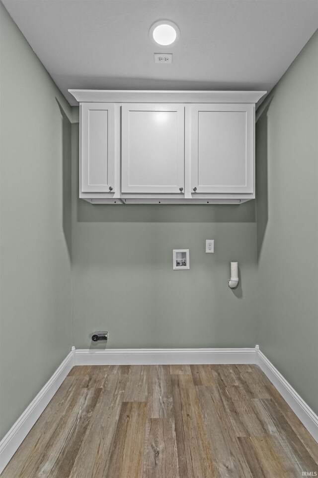 clothes washing area featuring cabinet space, baseboards, washer hookup, and wood finished floors