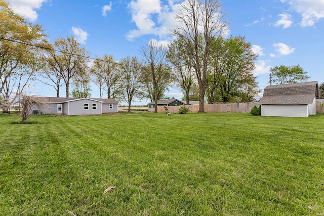 view of yard with fence, an outbuilding, and a shed