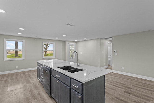 kitchen featuring light wood-style floors, a sink, baseboards, and dishwasher