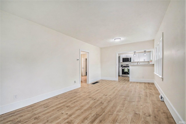 714 S 25th St, South Bend, IN 46615 - unfurnished living room with baseboards, visible vents, a sink, and light wood-style floors