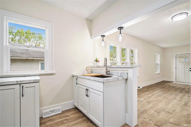 714 S 25th St, South Bend, IN 46615 - kitchen featuring visible vents, a peninsula, light wood-type flooring, light countertops, and a sink