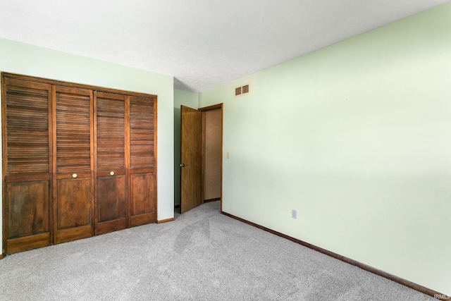 unfurnished bedroom featuring visible vents, baseboards, a closet, and light carpet