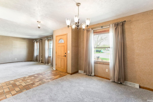 interior space with a chandelier, baseboards, visible vents, and plenty of natural light