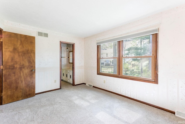 unfurnished bedroom featuring carpet floors, wallpapered walls, visible vents, and baseboards