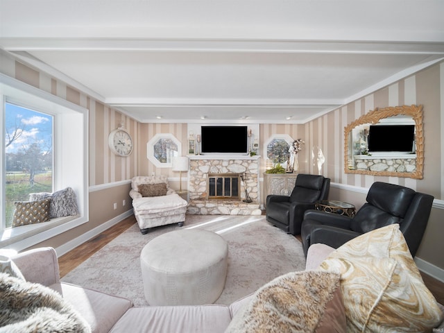 living area with baseboards, plenty of natural light, a fireplace, and wood finished floors