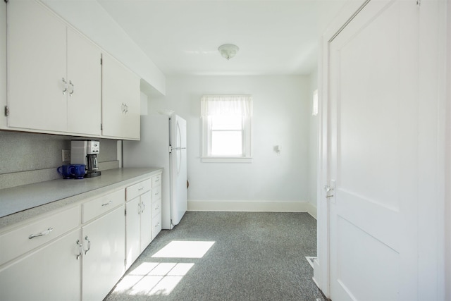 kitchen with light countertops, baseboards, white cabinets, and freestanding refrigerator