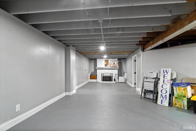 finished basement with baseboards and a brick fireplace
