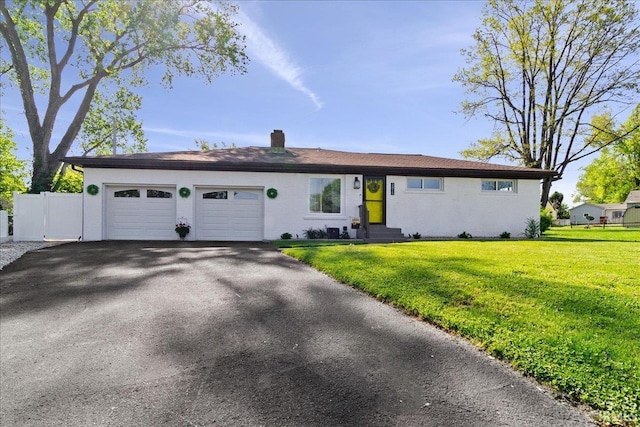 single story home featuring fence, an attached garage, aphalt driveway, a front yard, and a chimney