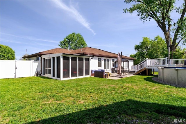 rear view of property featuring an outdoor pool, a sunroom, a fenced backyard, a yard, and a patio