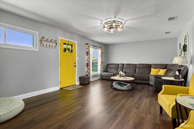 living area featuring baseboards, visible vents, and wood finished floors