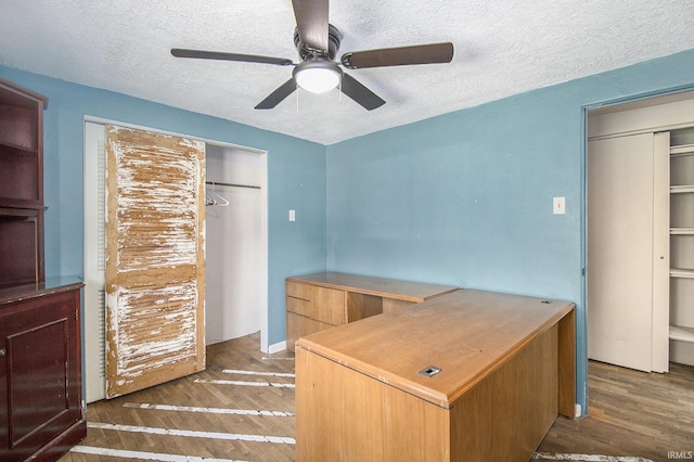 unfurnished office featuring a textured ceiling, ceiling fan, and wood finished floors