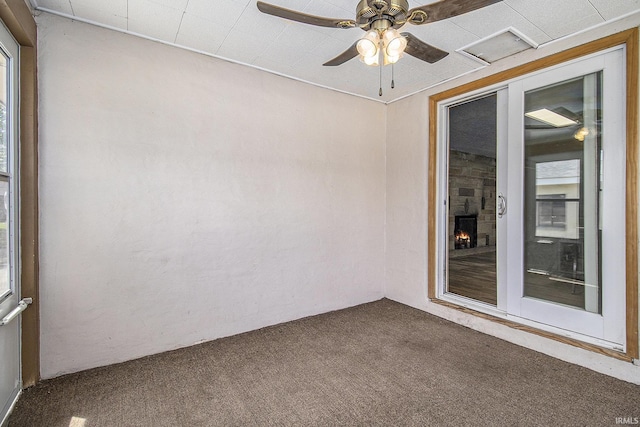 unfurnished room with carpet floors, ceiling fan, and a fireplace