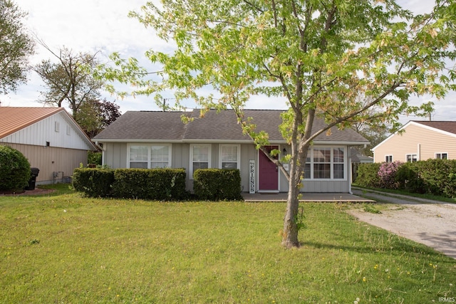 view of front of house featuring board and batten siding, roof with shingles, and a front yard